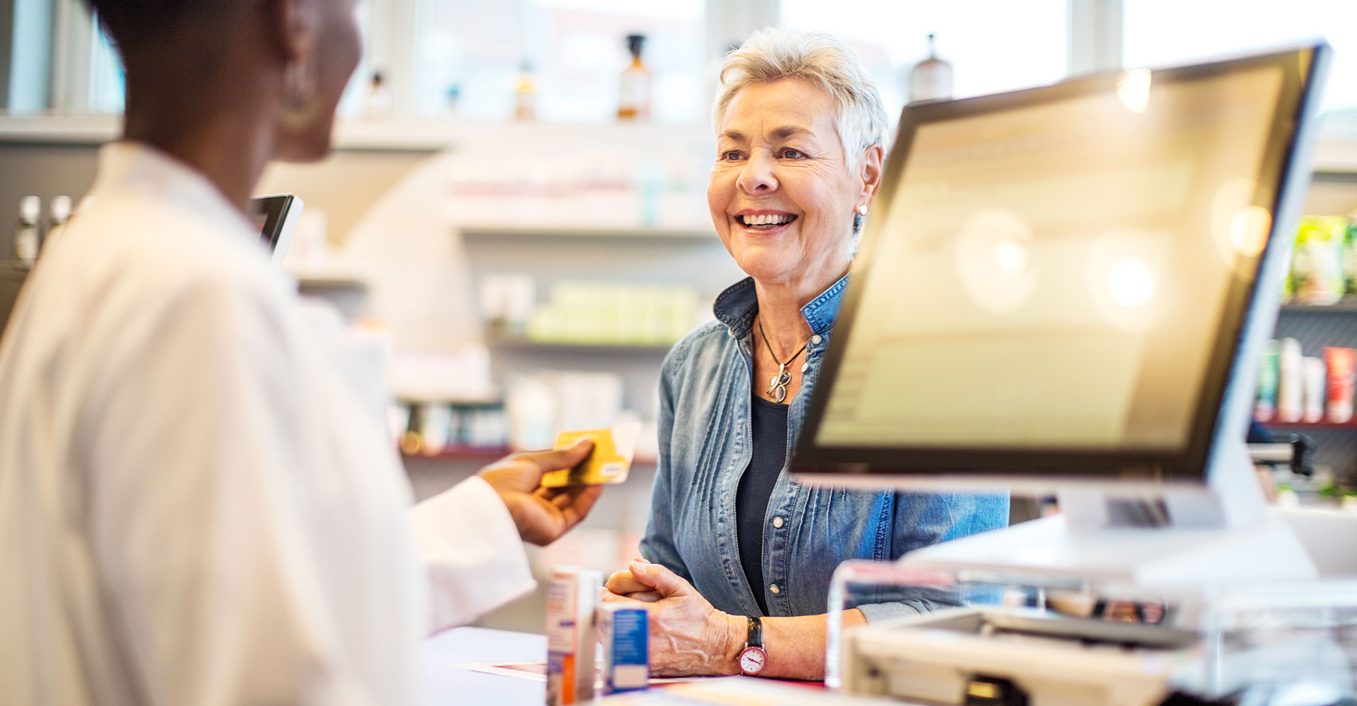 Customer speaking to pharmacist at prescription counter
