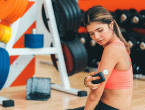 female using glucose monitor while sitting in front of weights