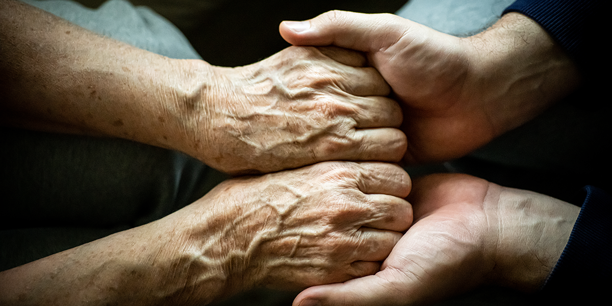 Two people comforting each other by holding hands.