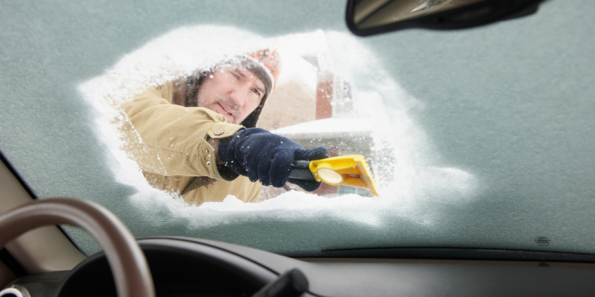 Man scraping down icy windshield