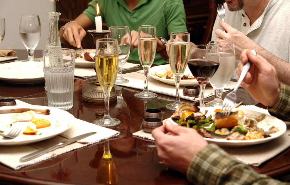 Family eating at dining table with full plate, champagne, and wine