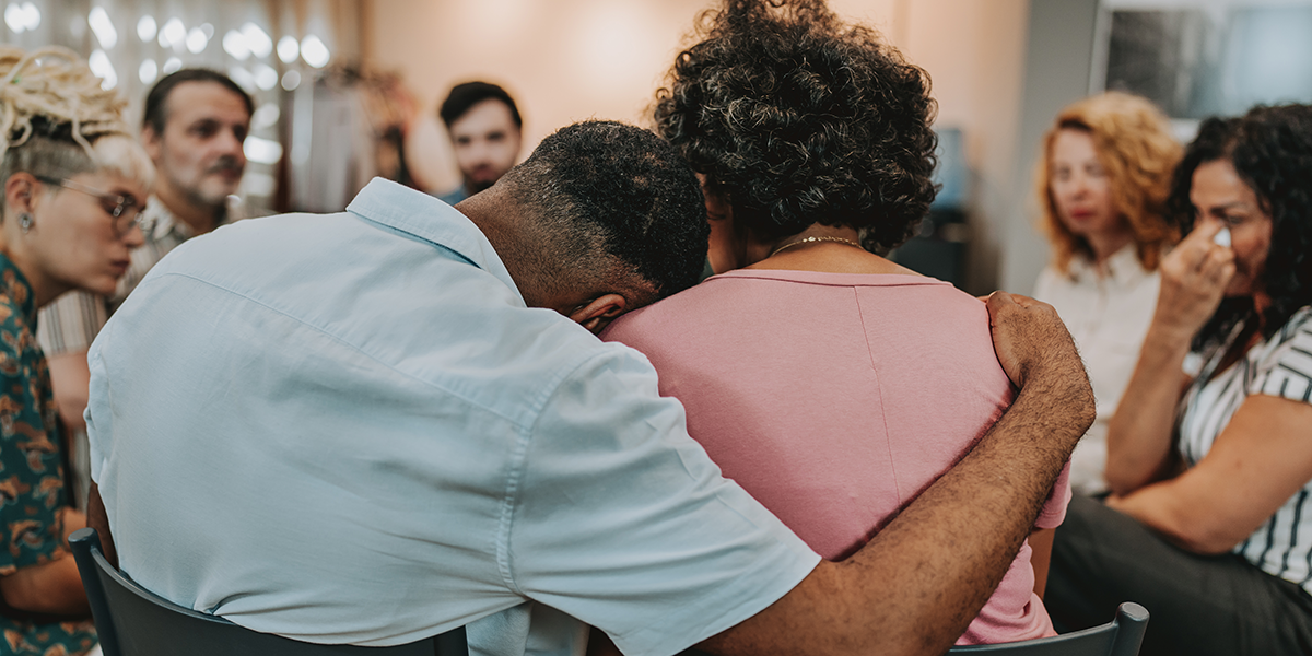 Two people hug during a grief support group meeting.