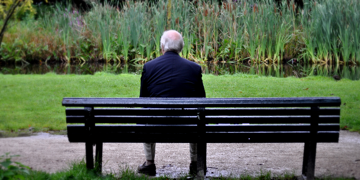 A older man sitting alone on a bench. Loneliness and social isolation can lead to real health issues.