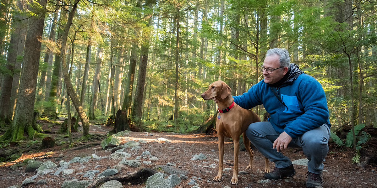 Man in wooded area with dog