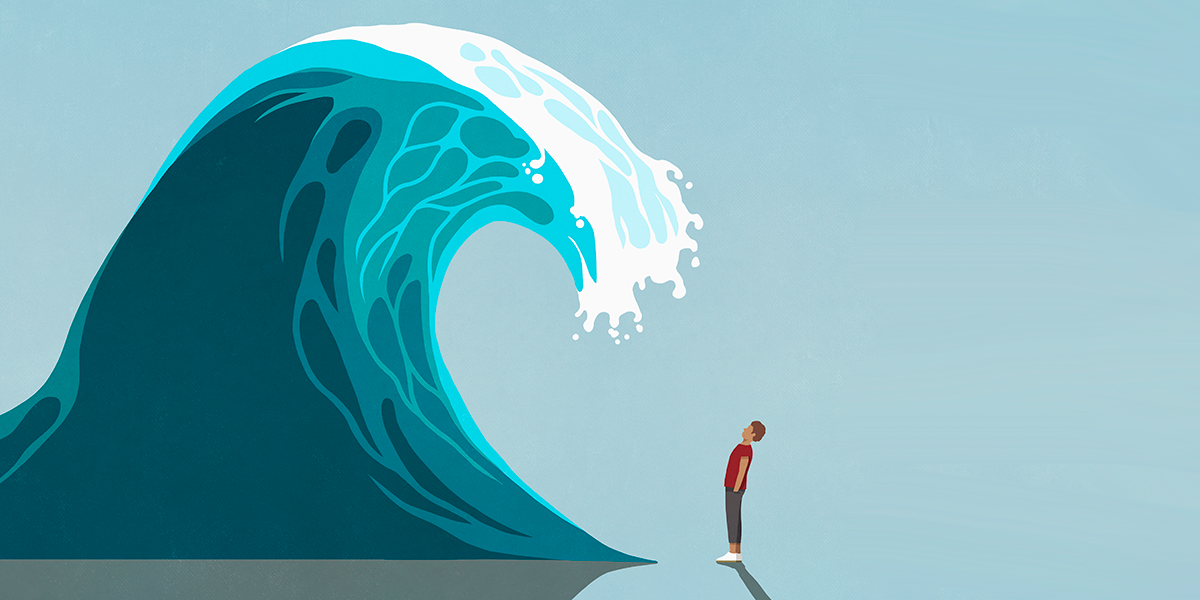 Chronic stress can age us faster. A man stands underneath a cresting wave.