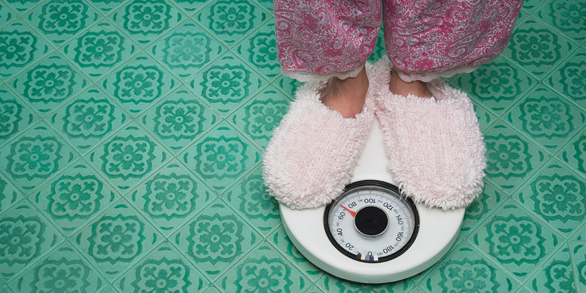 A woman stands on a scale; rapid weight loss can cause health problems.