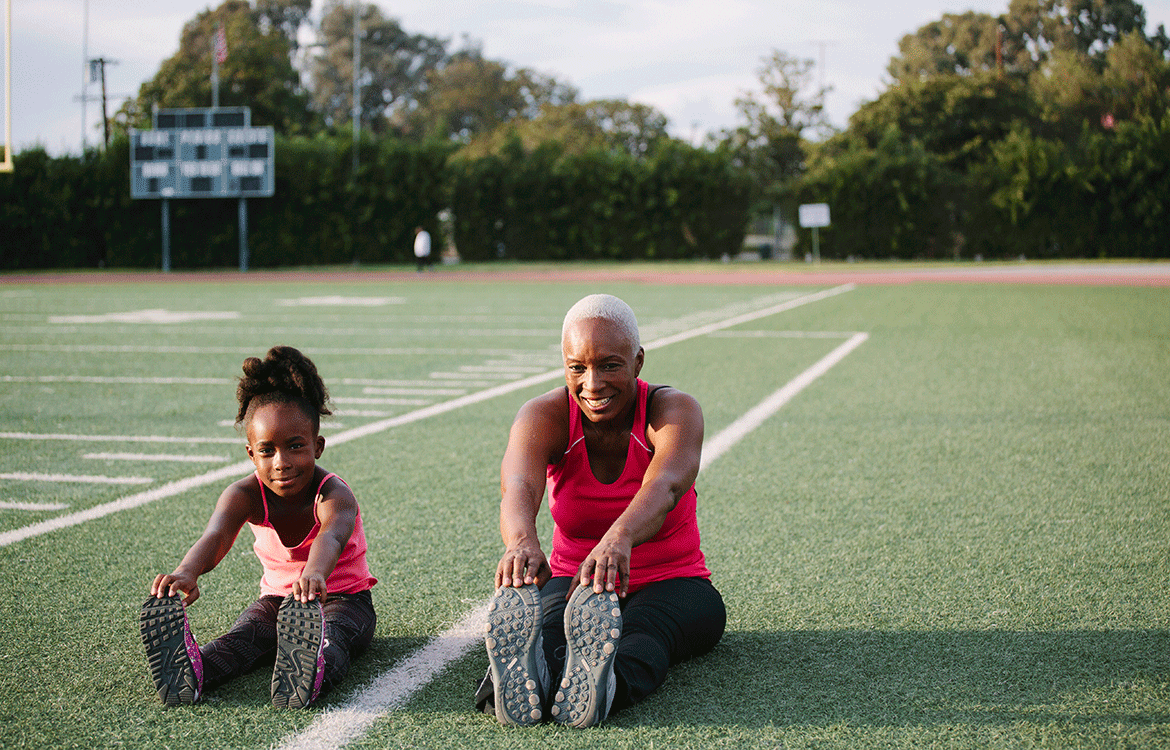 Grandmother and granddaughter stretching on football field