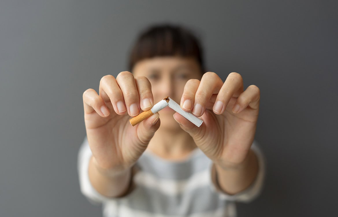 woman breaking cigarette in half