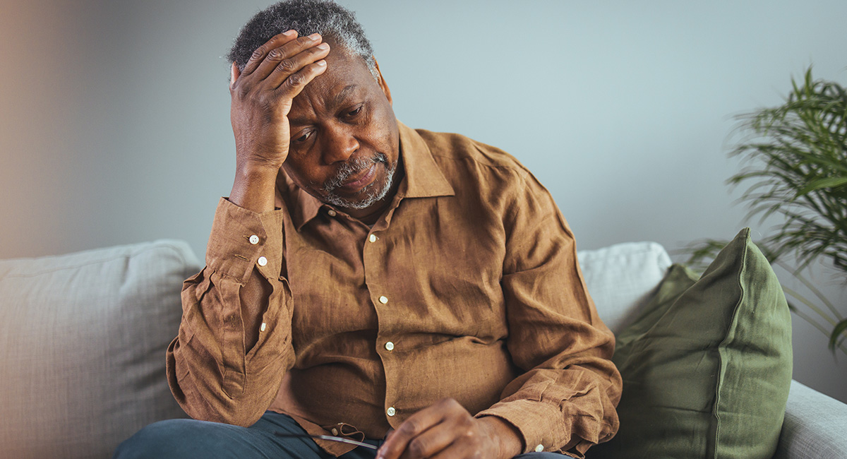 Man with headache sitting on couch.