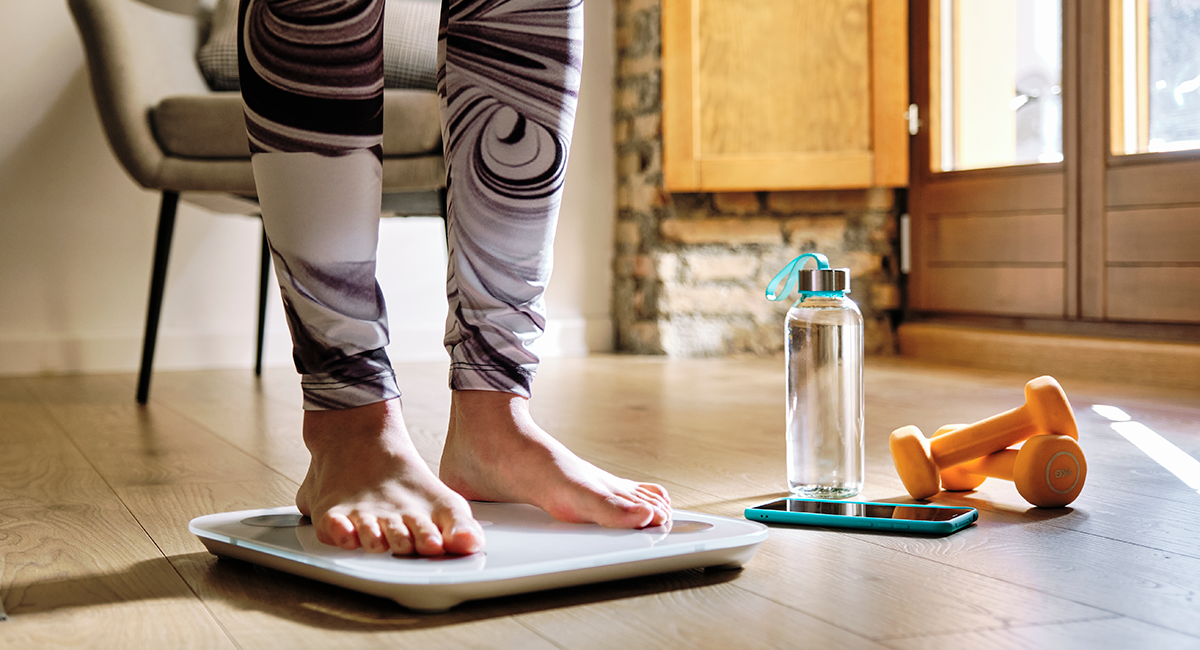 Woman standing on scale, trying to determine her weight.