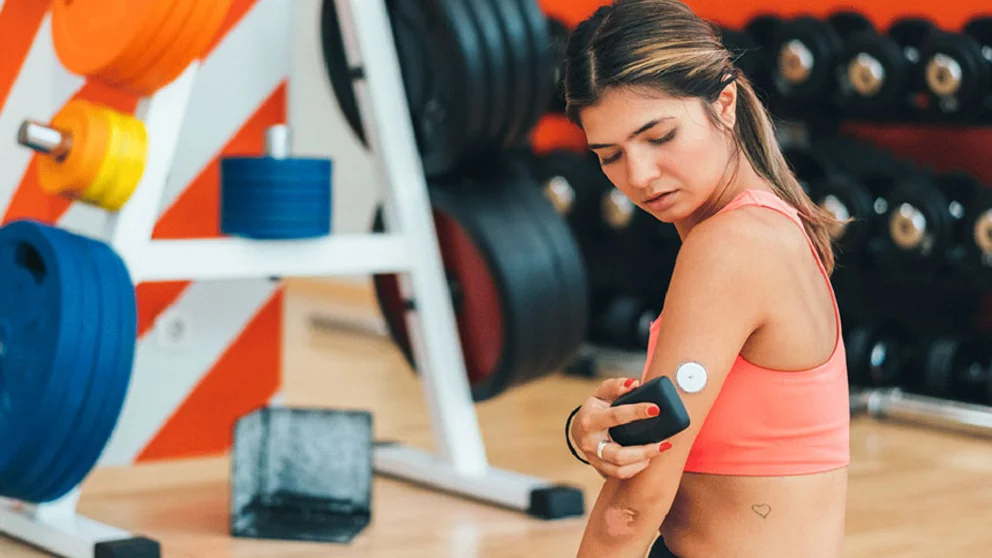 female using glucose monitor while sitting in front of weights