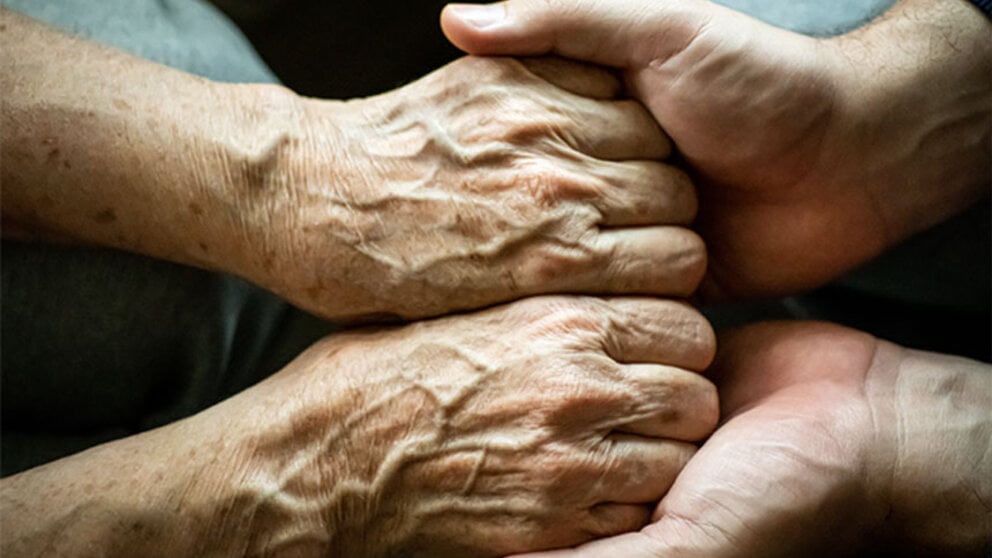 Two people comforting each other by holding hands.