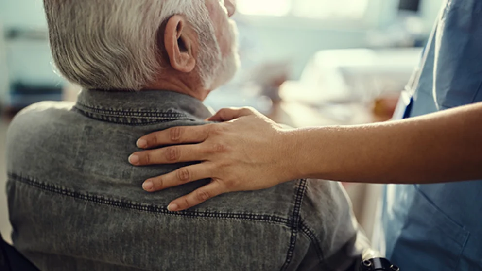 A nurse consoling an elderly man