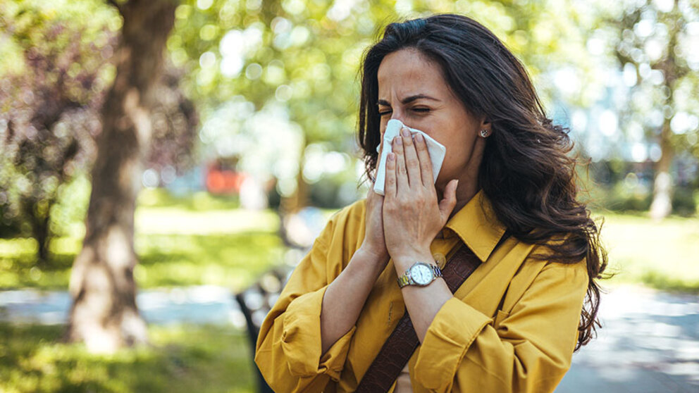 woman blowing her nose outside