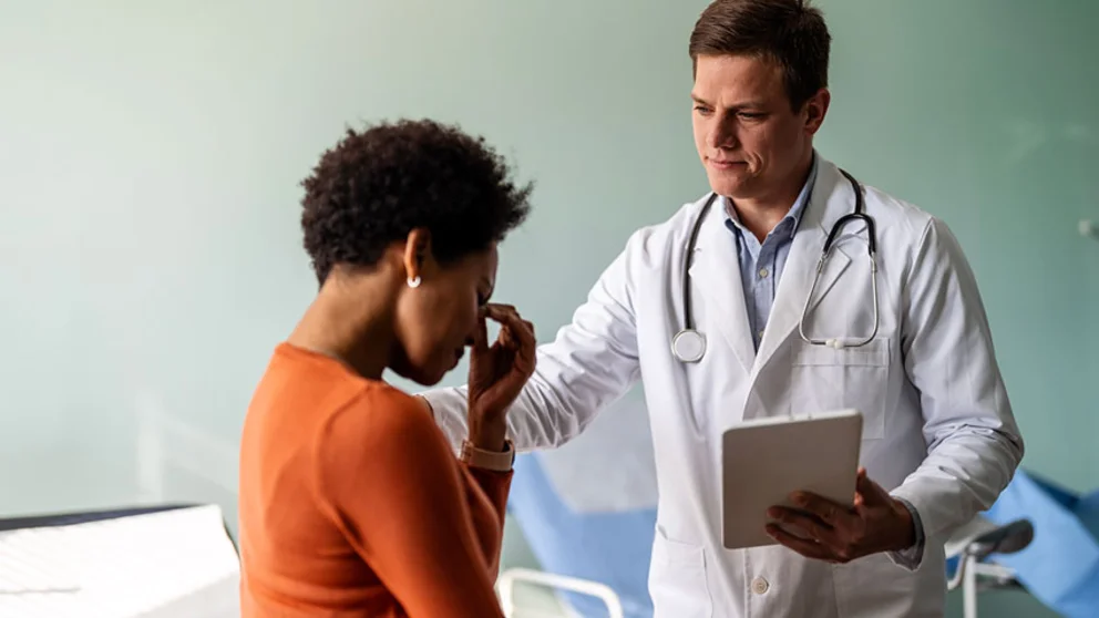 Woman in orange shirt talking to doctor