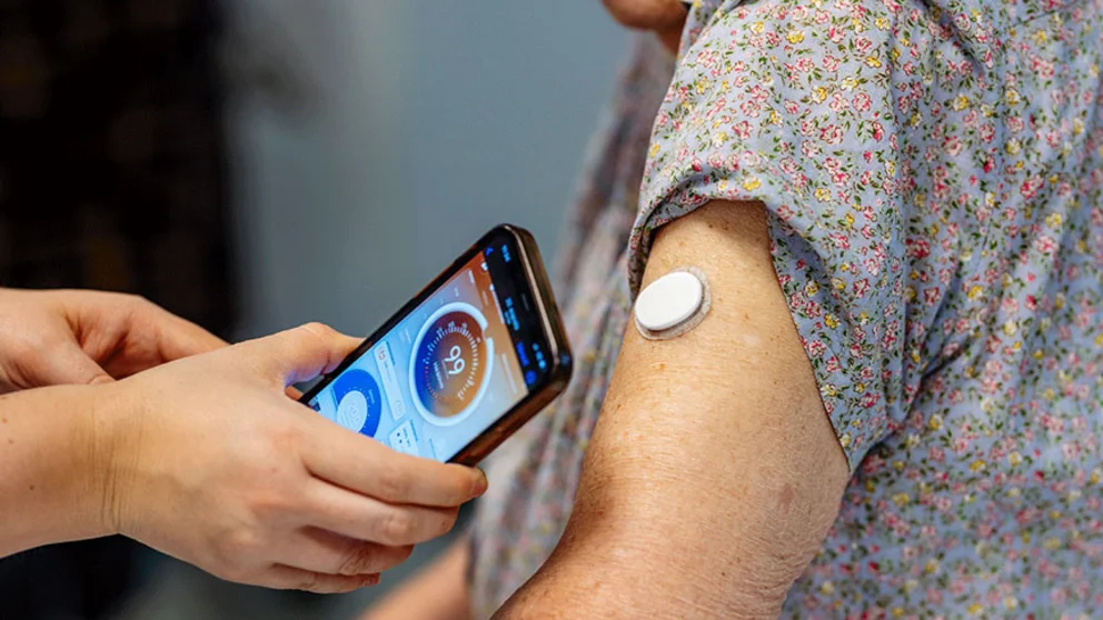 nurse teaching older woman how to use a CGM