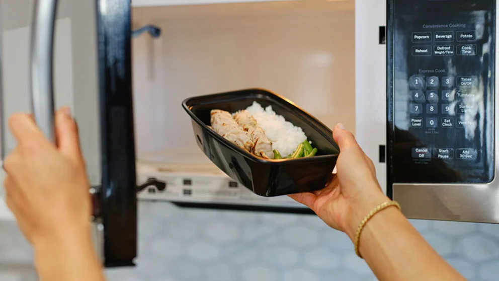 woman removing food from microwave