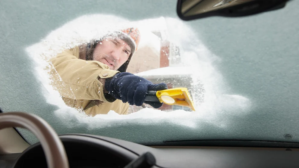 Man scraping down icy windshield