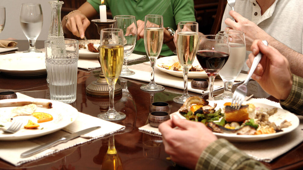 Family eating at dining table with full plate, champagne, and wine