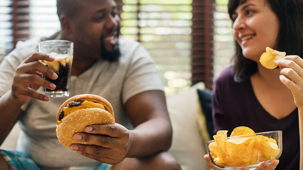 Overweight couple eating unhealthy food