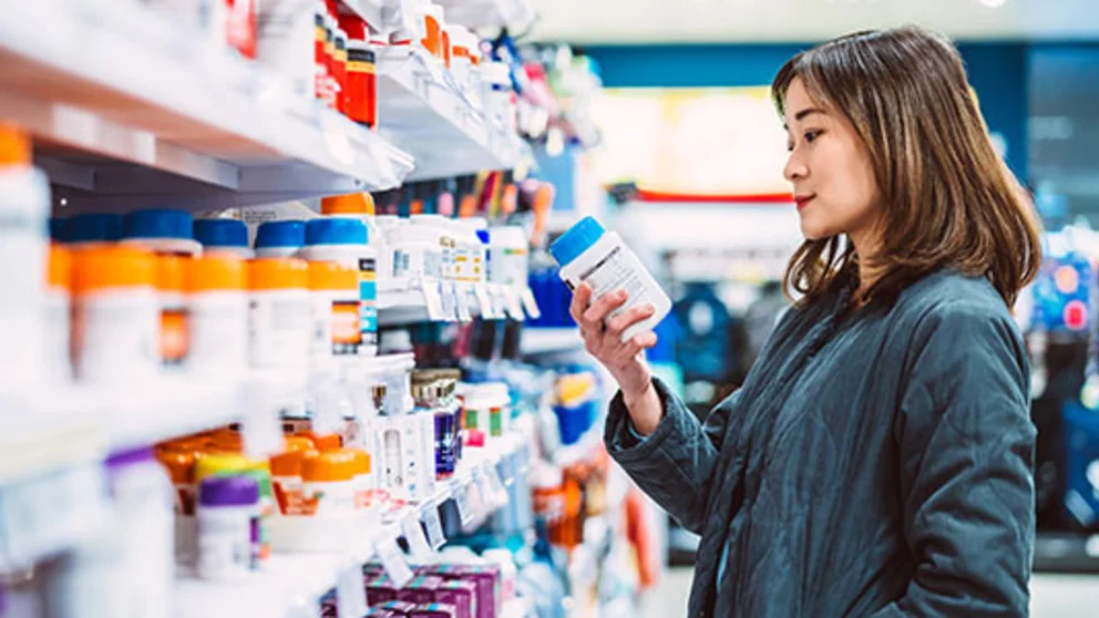 A woman looking at supplements in the pharmacy. These supplements may not help improve your health.