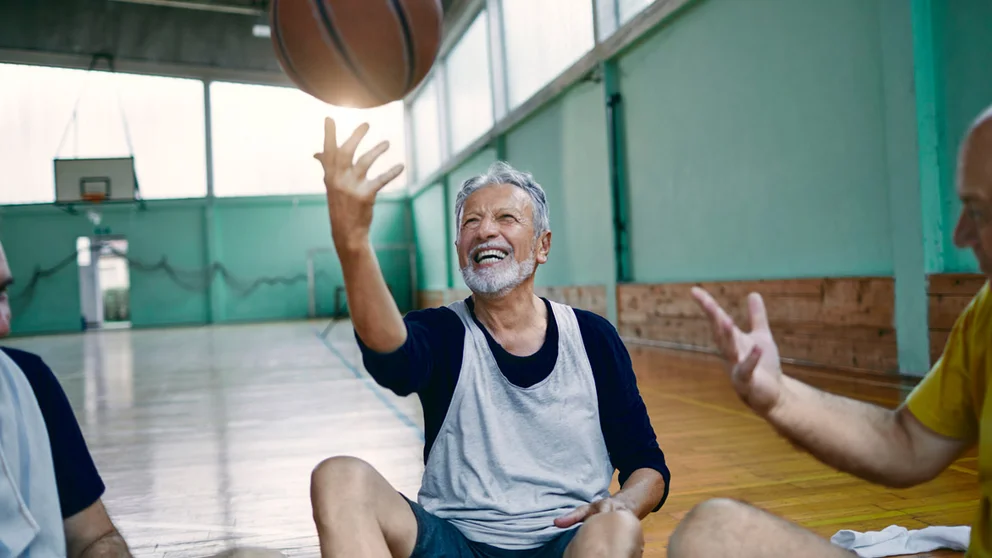 middle aged man tossing basketball into the air