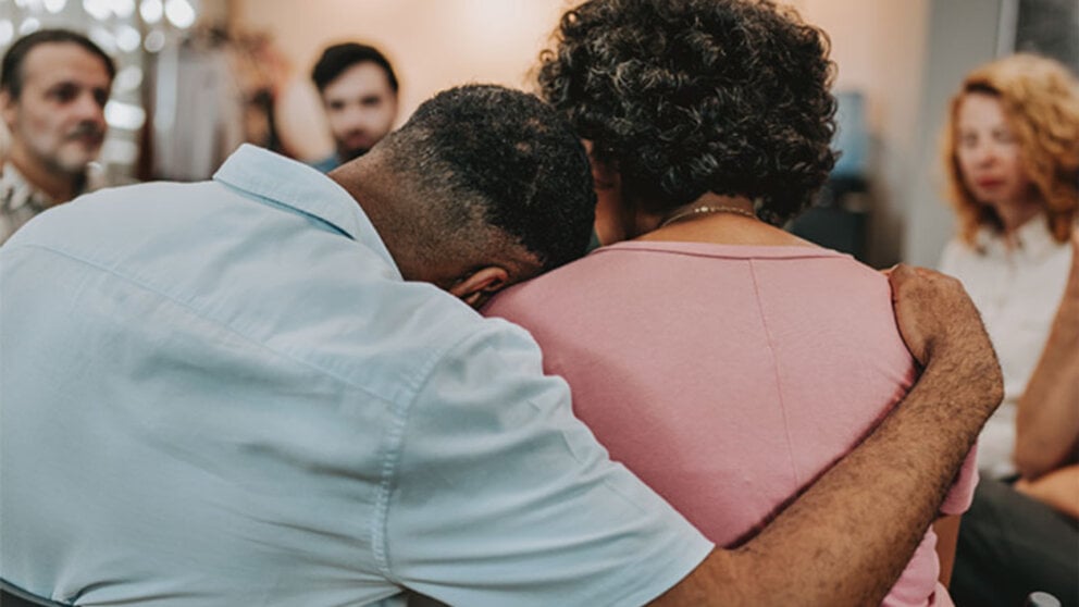 Two people hug during a grief support group meeting.