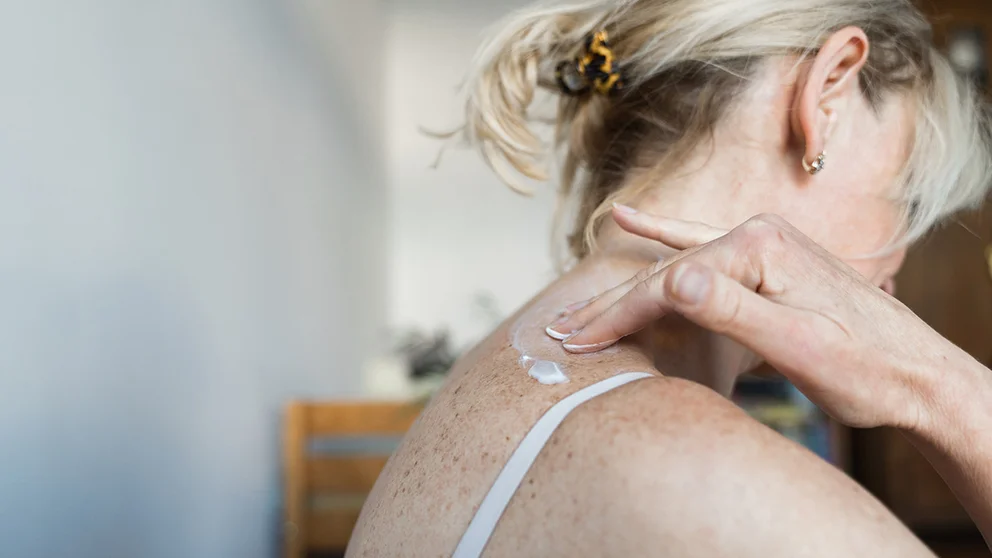 Woman applies lotion to her skin
