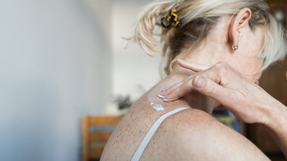 Woman applies lotion to her skin
