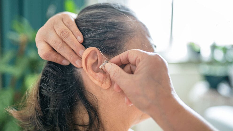 Woman putting on a hearing aid