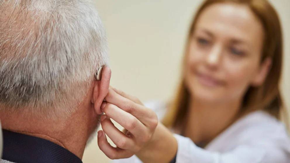 Doctor fitting patient for hearing aid