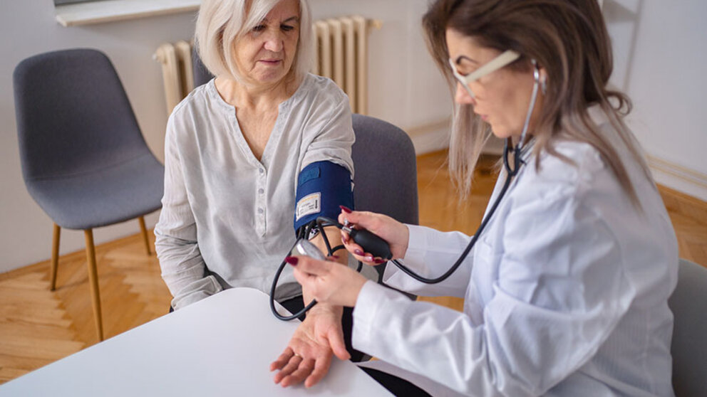 Physician taking blood pressure of female patient