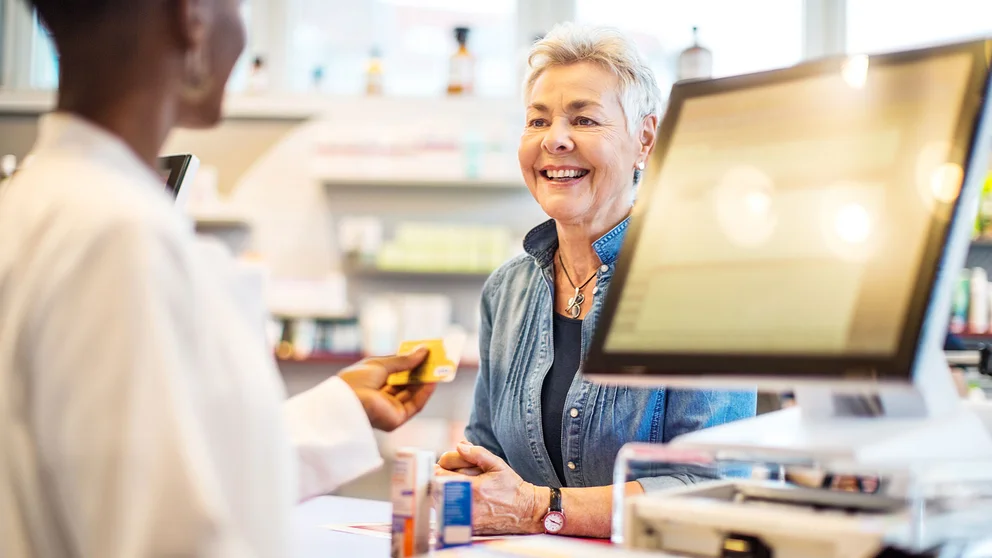 Customer speaking to pharmacist at prescription counter