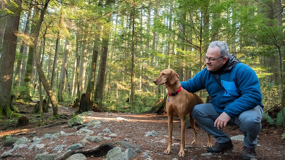 Man in wooded area with dog