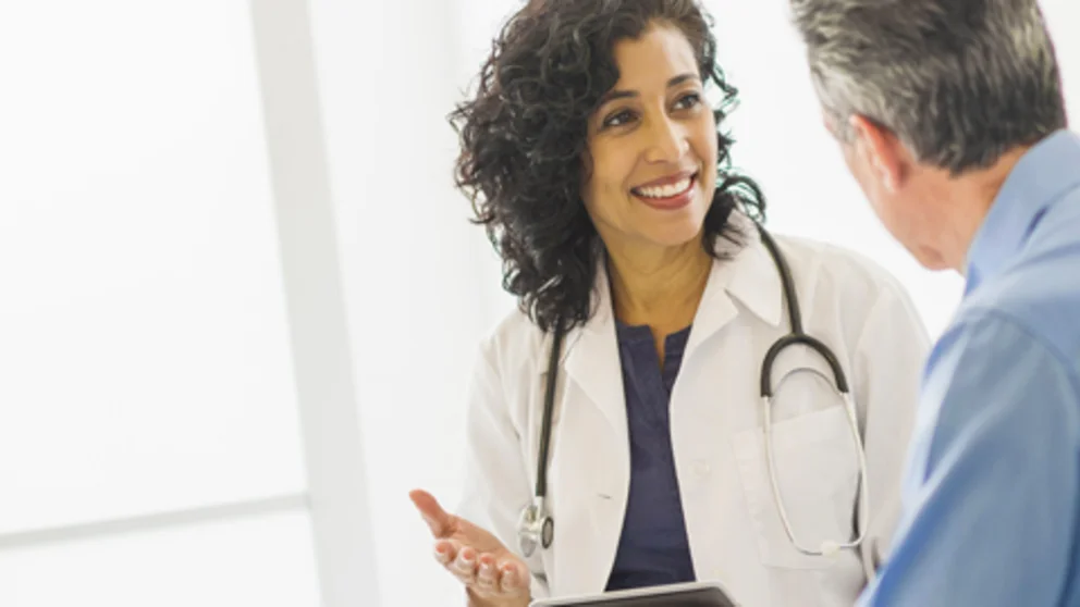 Healthcare provider listening to a male patient during a one-on-one consultation.