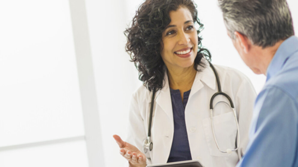 Healthcare provider listening to a male patient during a one-on-one consultation.