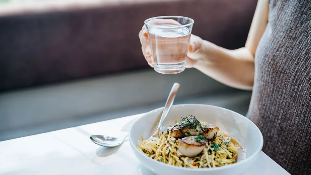 Women drinking water, eating pasta with seafood