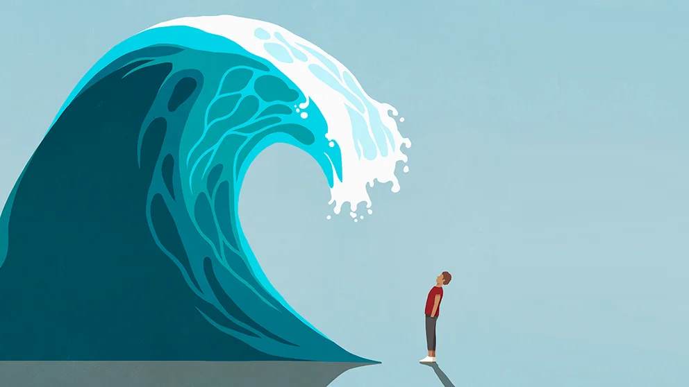 Chronic stress can age us faster. A man stands underneath a cresting wave.