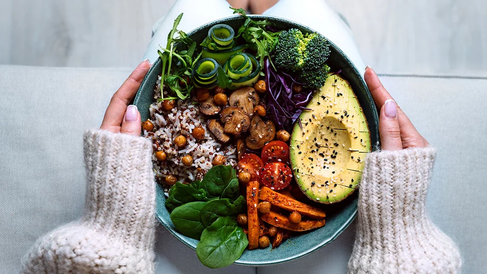 Woman eating a plate of vegetables. Plant-based diets have substantial health benefits.