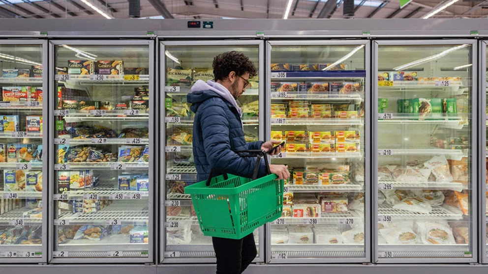 person in grocery aisle checking their phone