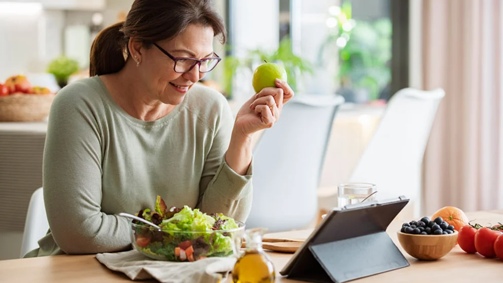woman eating salad with fruit while reading