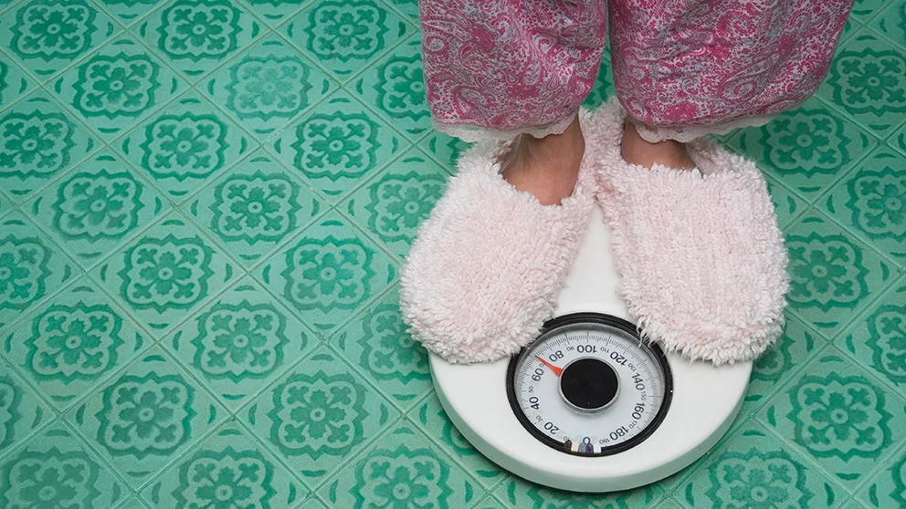A woman stands on a scale; rapid weight loss can cause health problems.
