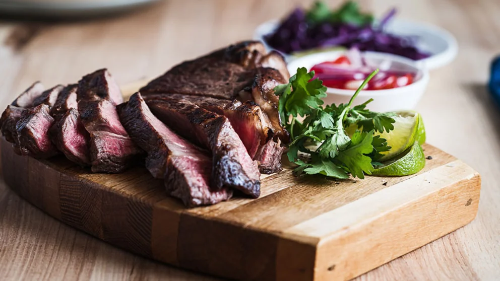 Cooked red meat on cutting board with condiments