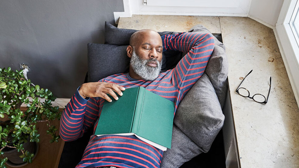 Man napping on couch with book and glasses