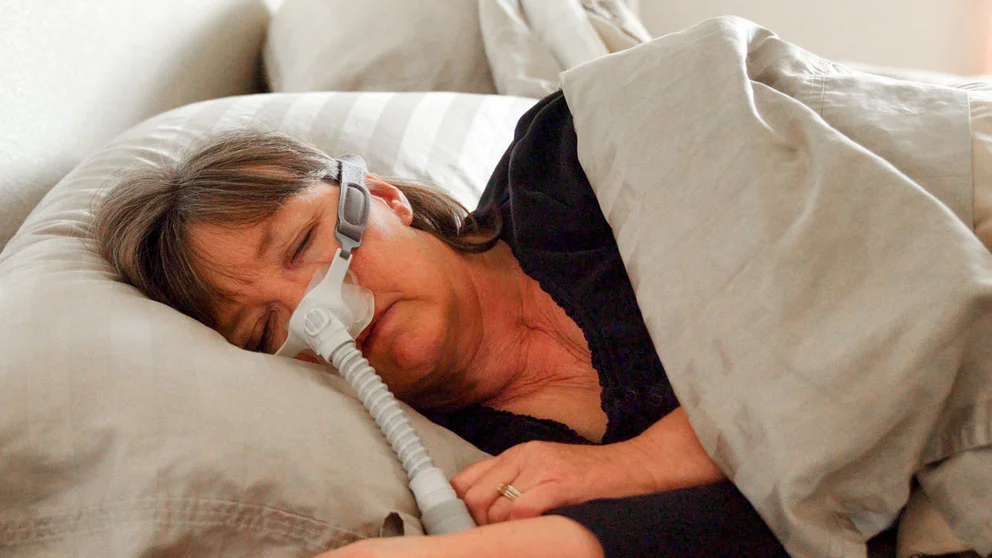Older woman asleep in bed with a CPAP mask on
