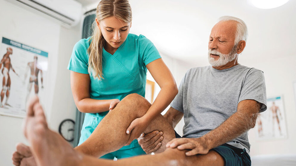 Physical therapist stretching older man