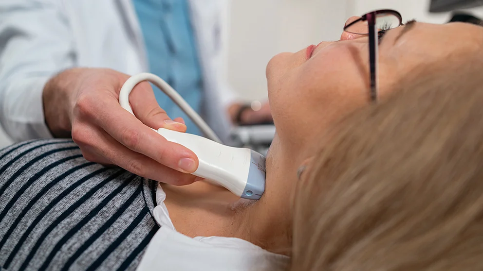 A doctor performs a thyroid ultrasound.