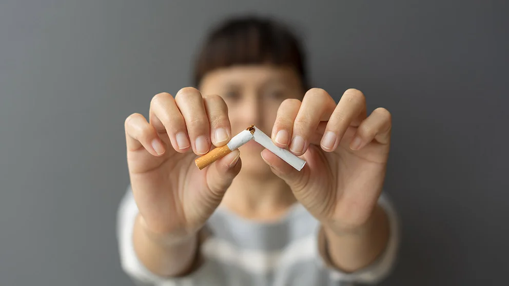 woman breaking cigarette in half