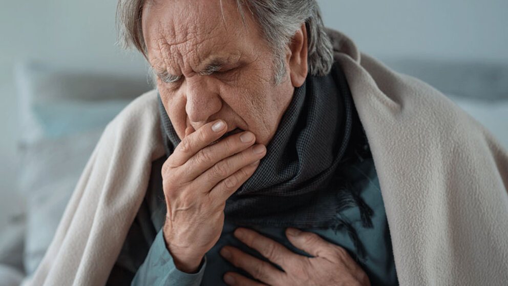 elderly person coughing into hand