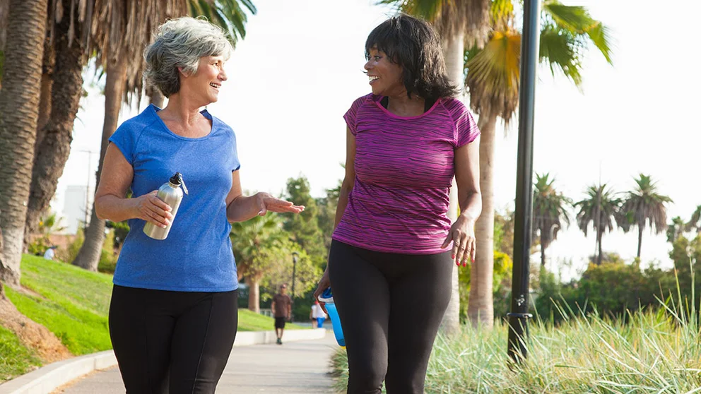 two middle aged women walking and holding water bottles